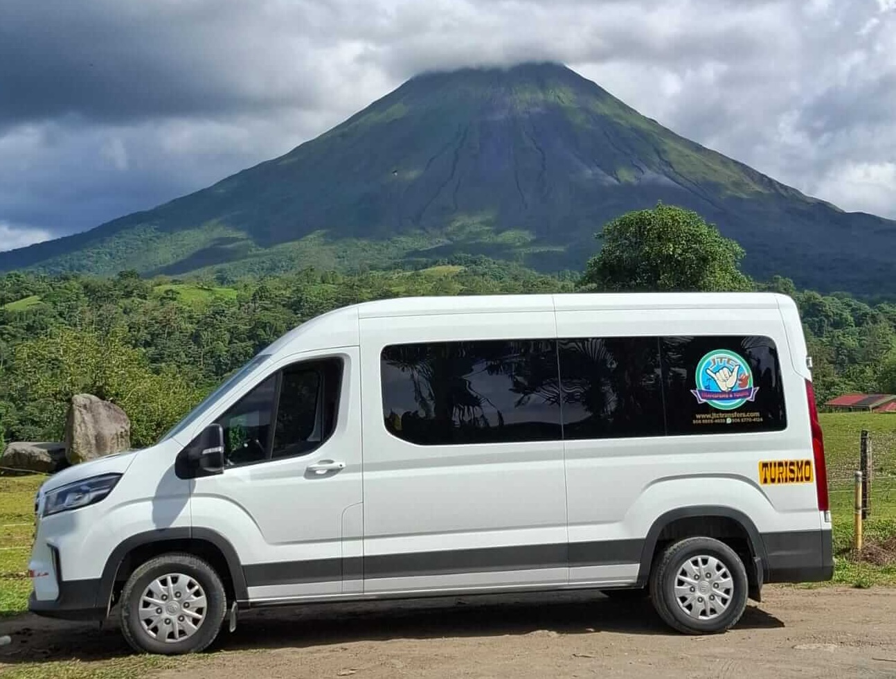 http://White%20private%20shuttle%20van%20parked%20near%20Arenal%20Volcano%20with%20lush%20highland%20vegetation%20in%20the%20foreground.%20La%20Fortuna,%20Costa%20Rica