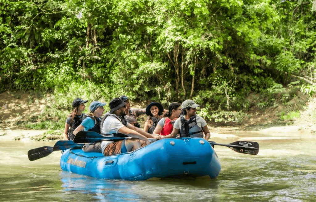 Group of rafters on a blue inflatable raft floating down a calm jungle river during the Safari Float River Tour near La Fortuna, Costa Rica